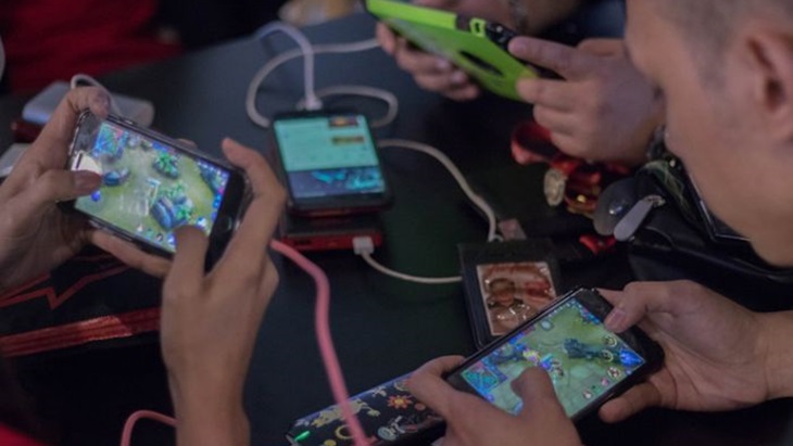Anak Tongkrongan Bermain Game Bareng di Kafe Anak muda sedang nongkrong sambil bermain game mobile bersama teman di kafe modern
